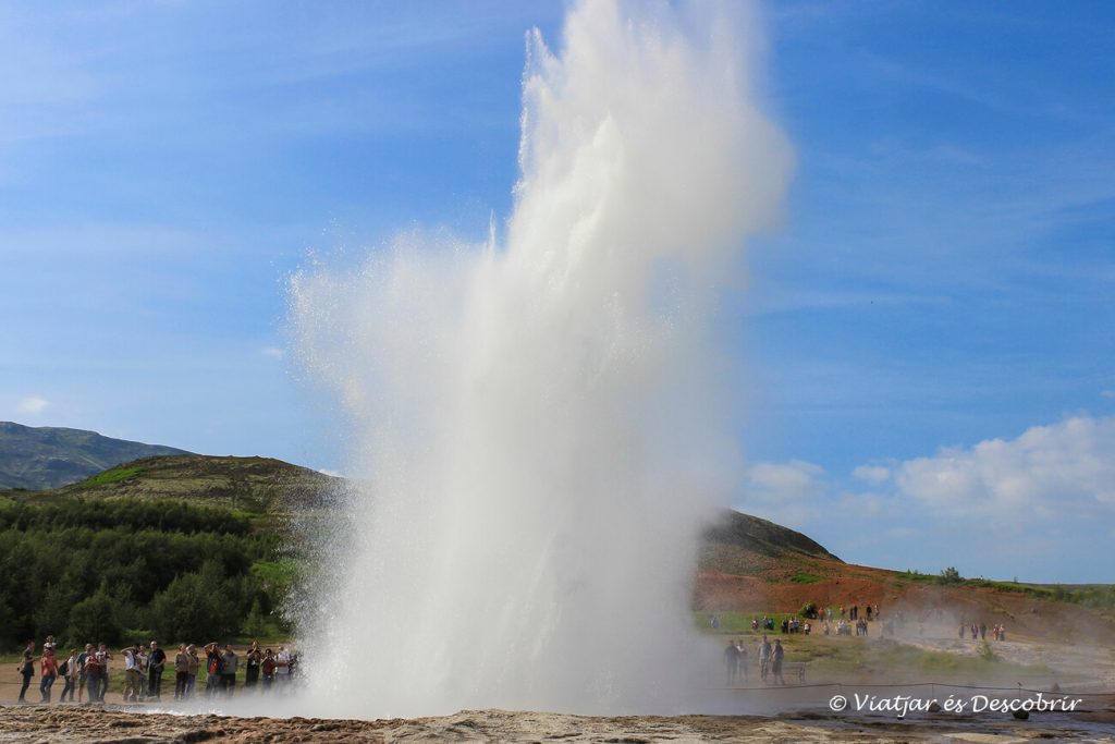 el géiser strokkur expulsando agua a una altura superior a diez metros y rodeado de turistas