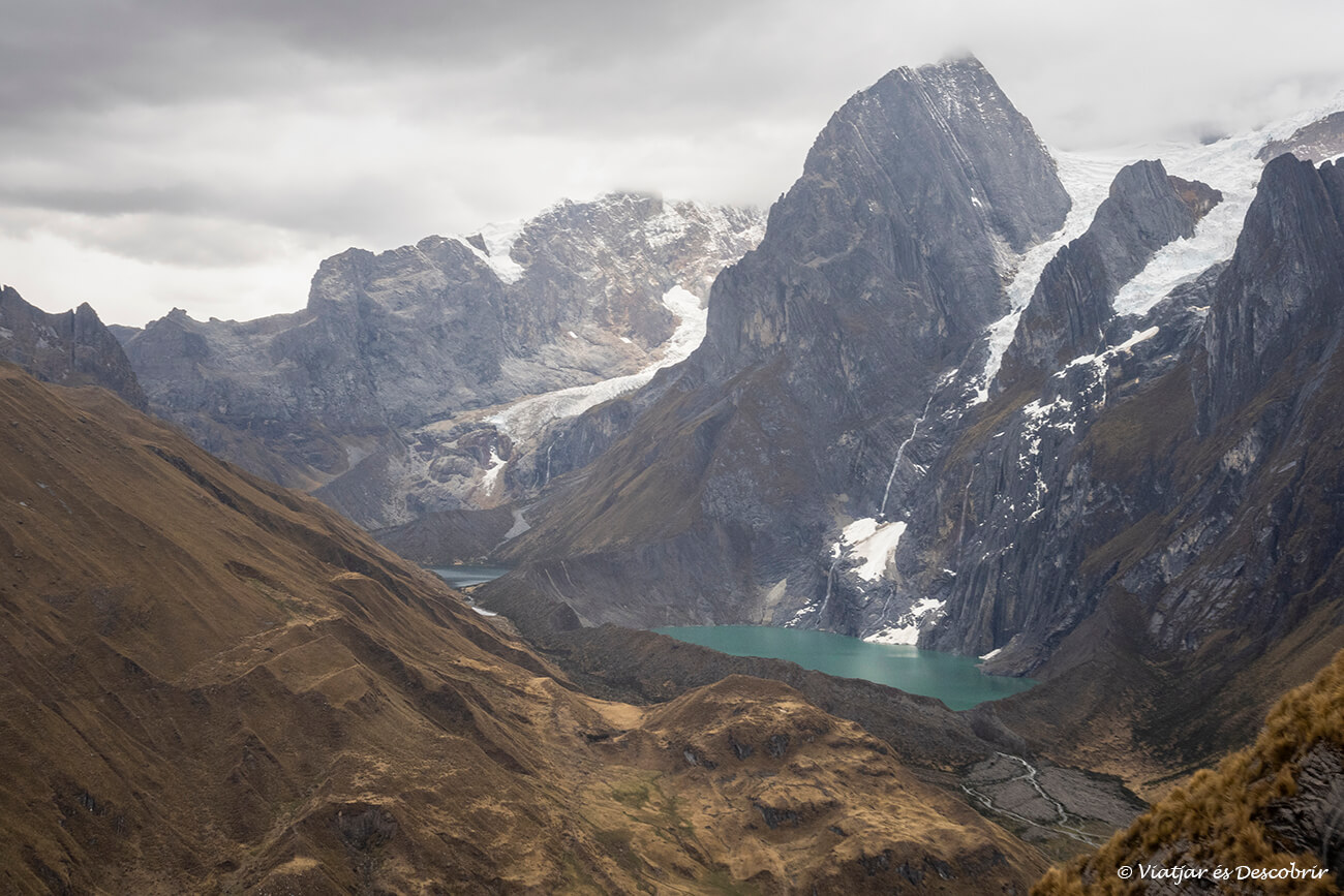 laguna turquesa y montaña vertical con glaciares durante el trekking del Huayhuash por libre
