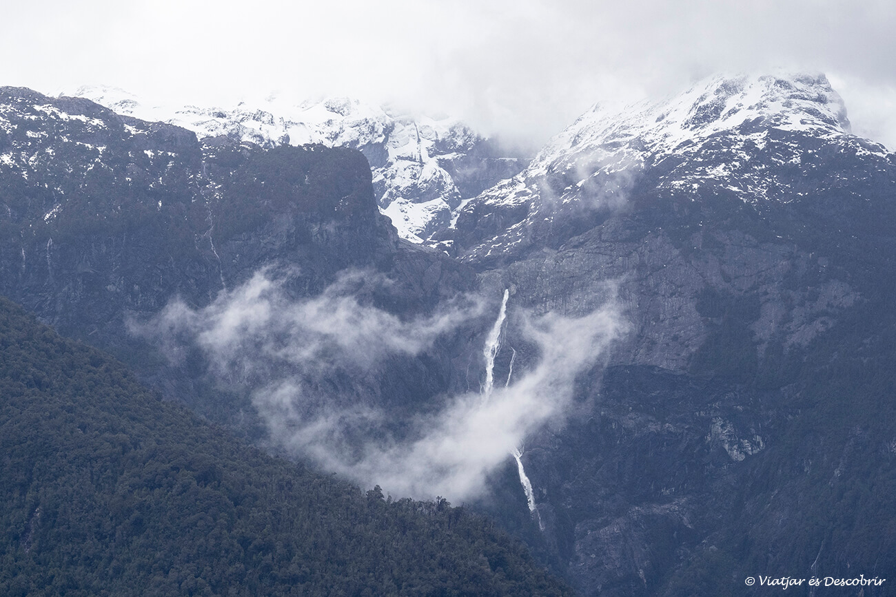 vista de montañas nevadas y cascadas en la barcaza de la Carretera Austral bimodeal que permite ir de Hornopirén hasta Caleta Gonzalo