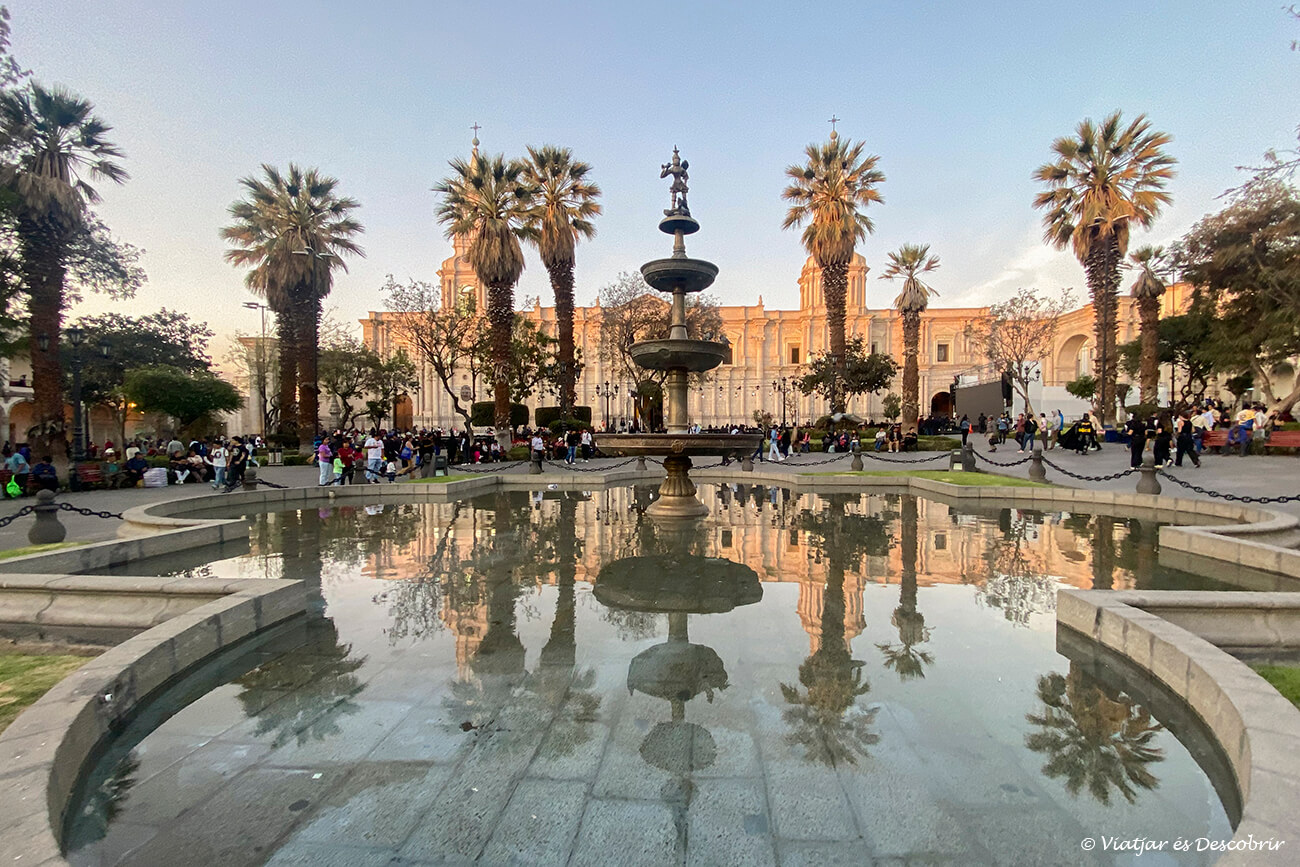 vista de la fuente de la Plaza de Armas de Arequipa con los edificios reflejados durante la puesta de sol
