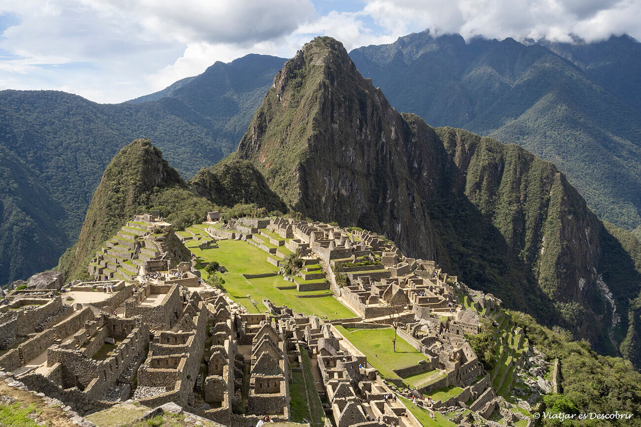 vista clásica del Machu Picchu durante un día soleado con algunas nubes y una muestra de que viajar a Perú en septiembre es una buena idea